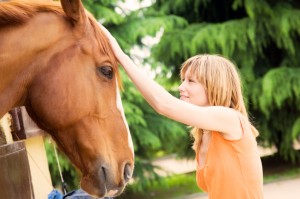 girl petting horse while volunteering